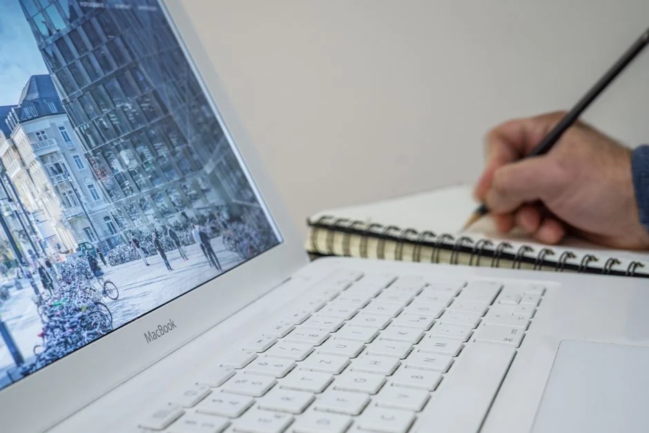 Mains saisissant du texte sur un ordinateur portable, avec des graphiques de cryptomonnaies et l’écran d’un smartphone visibles, dans un univers axé sur la finance numérique.
